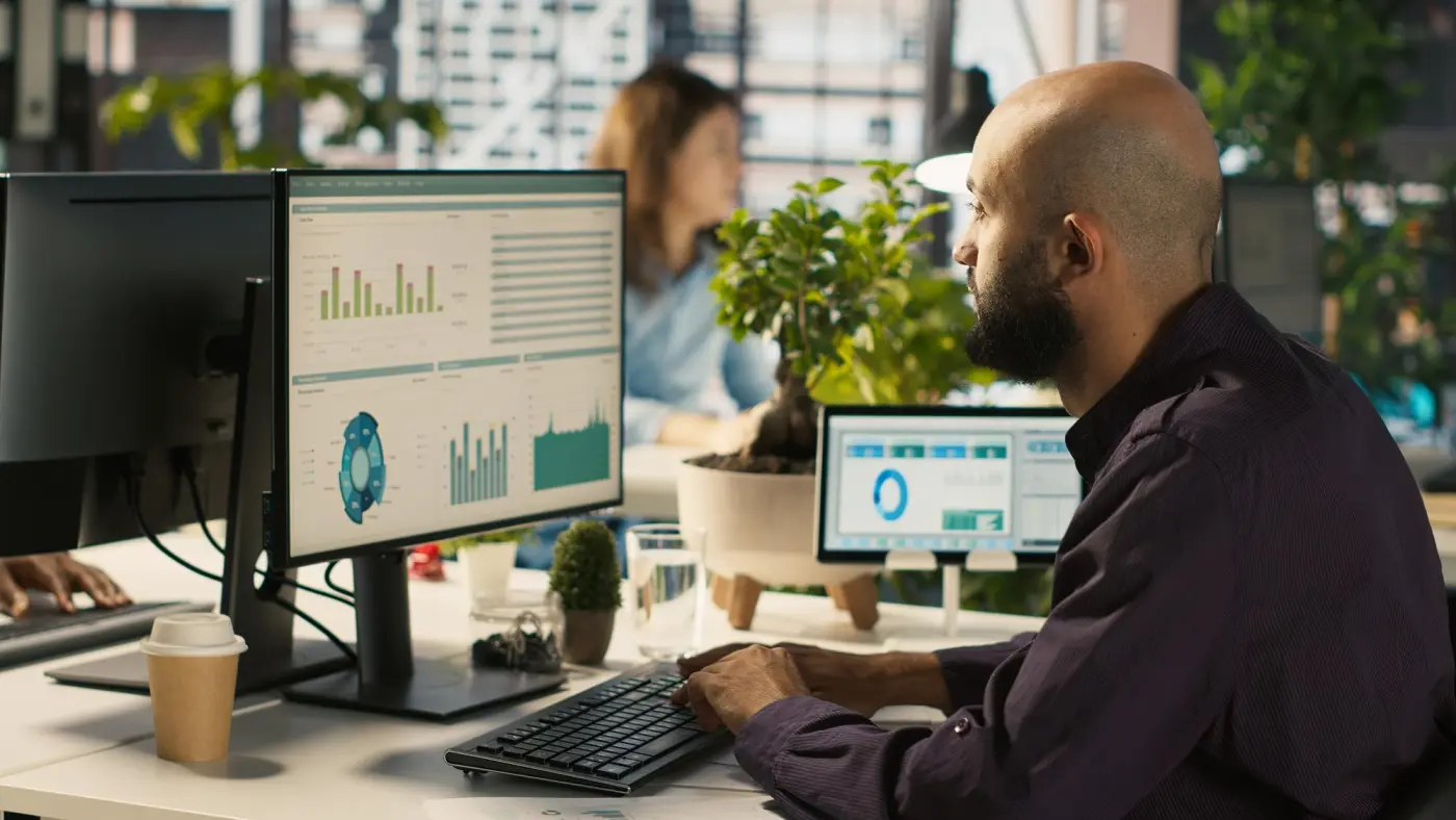 A developer at a desk with two monitors of dashboards