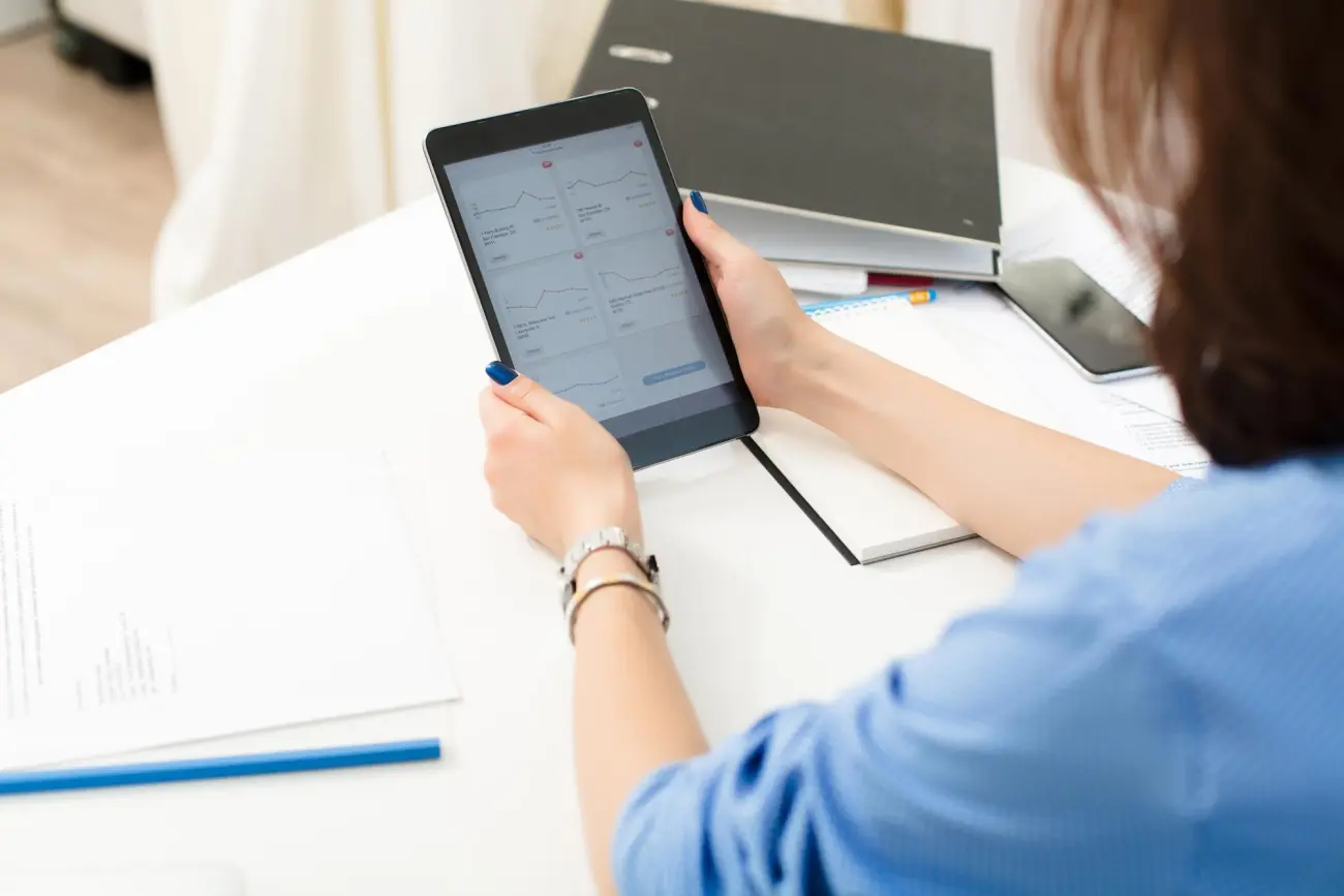 A woman reading a report on a tablet at a desk